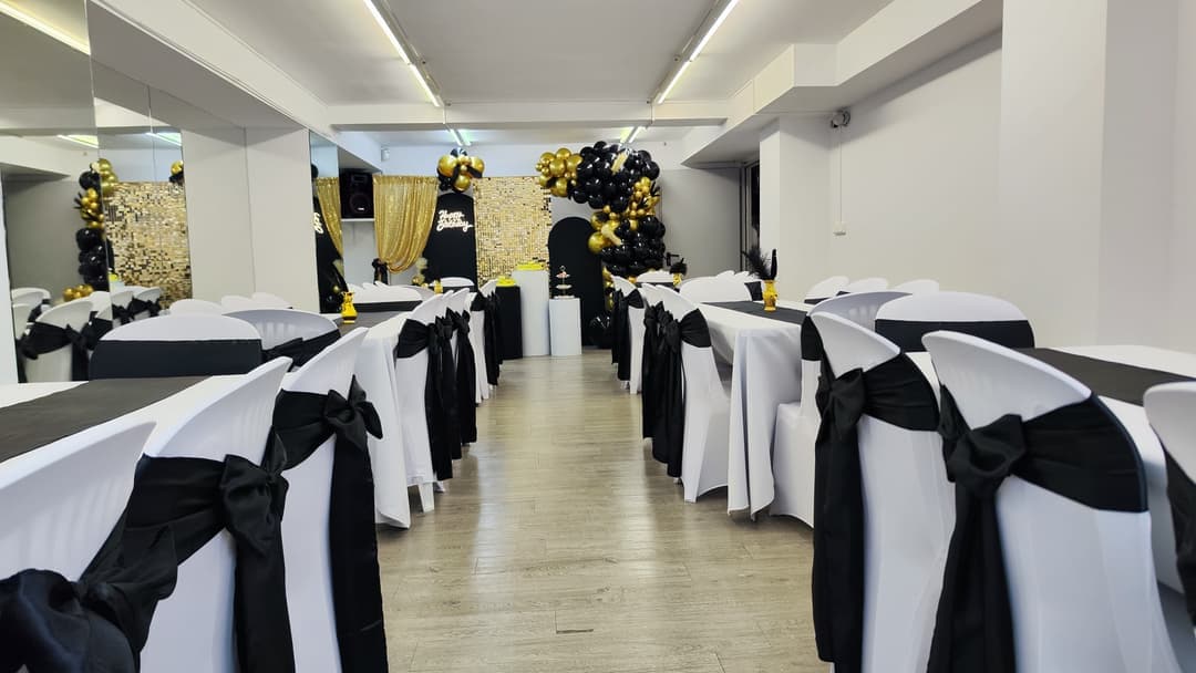 Salón de NEOX montado para un banquete, con mesas vestidas en blanco y negro y un fondo de lentejuelas doradas