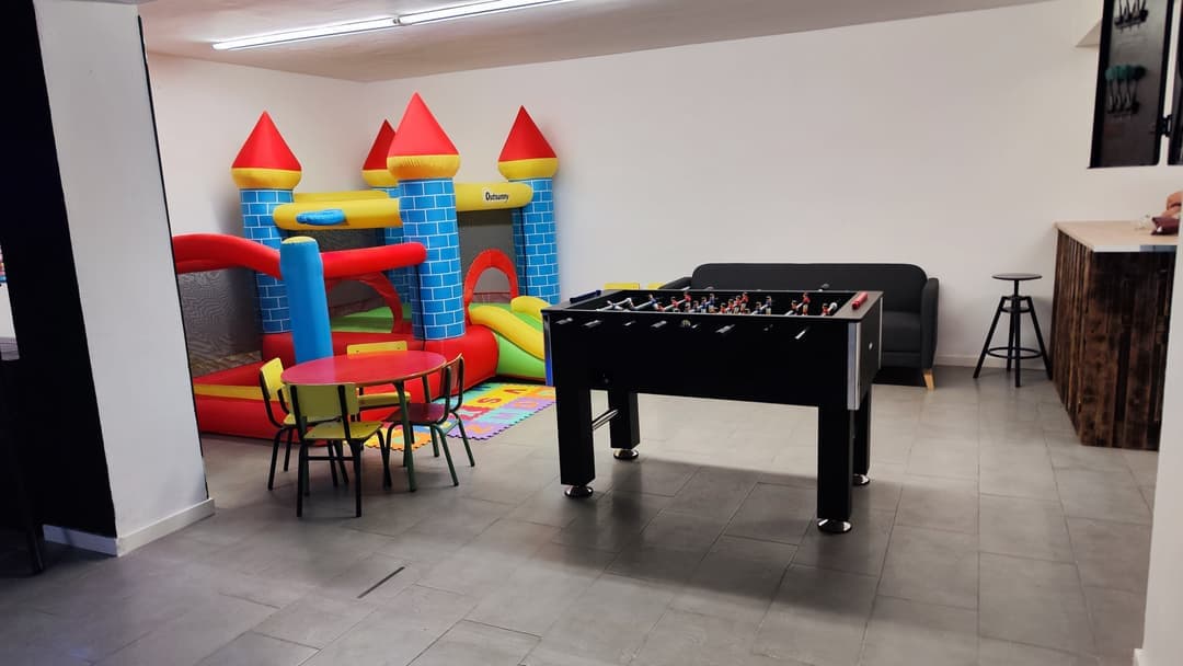 Zona infantil con castillo hinchable, futbolín y mesa para niños